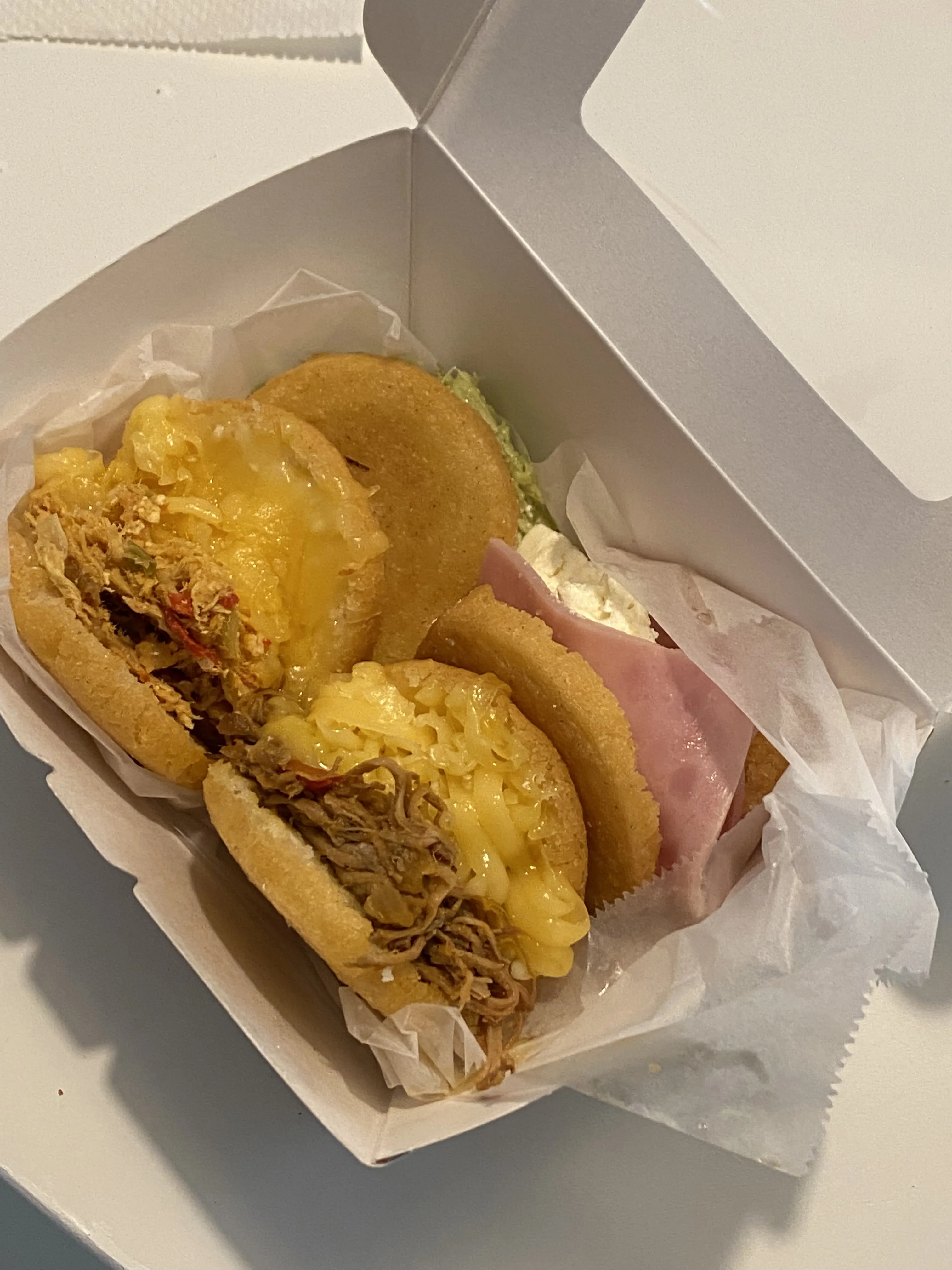 A takeout box of gorditas from Tacopolis: thick, fluffy corn pockets stuffed with ham and cheese, mac and cheese, and shredded meat.