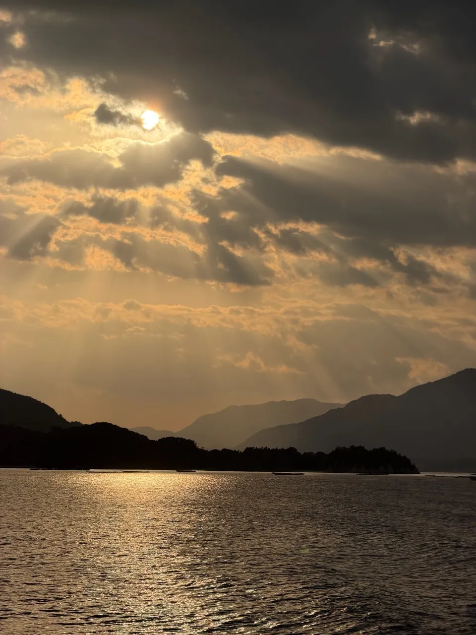 Sun breaking through clouds in long rays over the silhouetted islands of the Seto Inland Sea