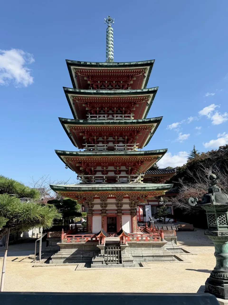 An ornate five-story vermillion-and-green pagoda under a blue sky at Kosanji Temple