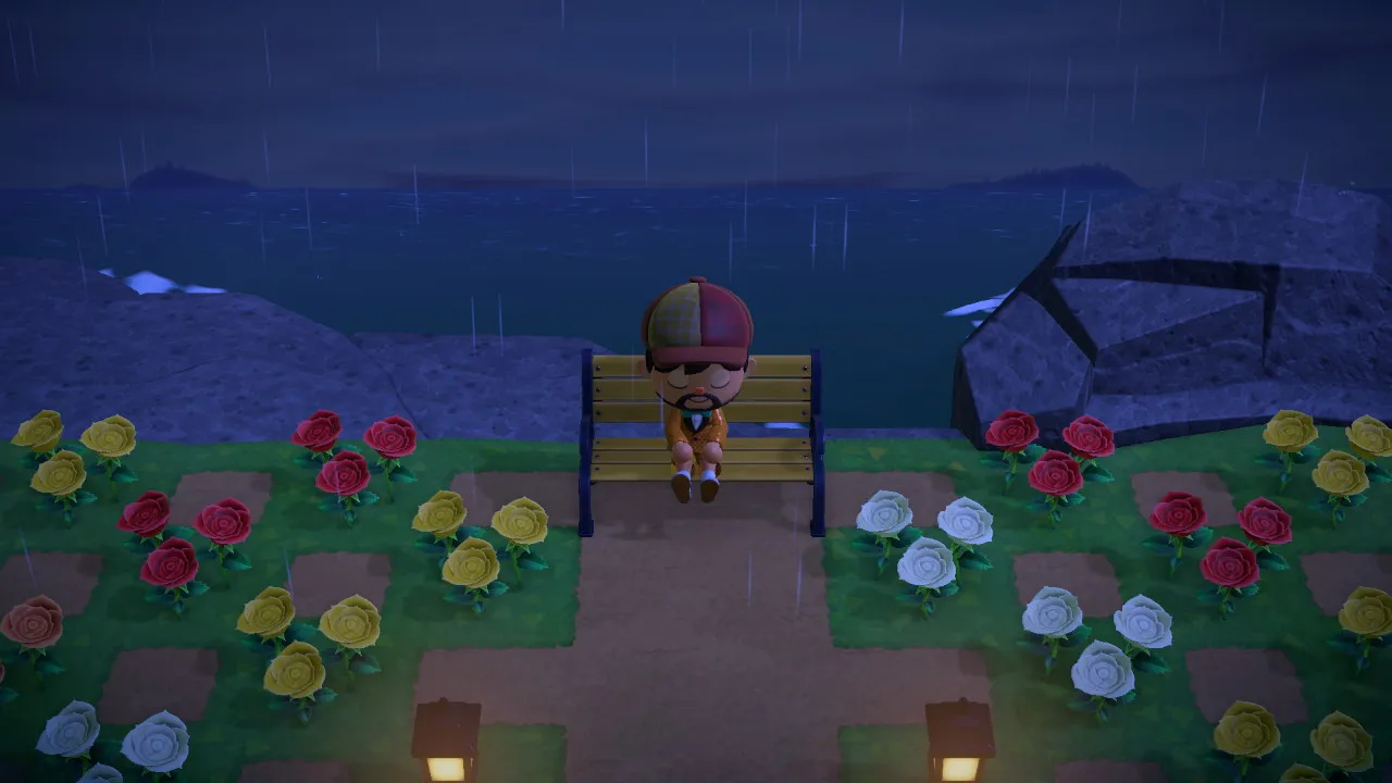 A formal rose garden on a cliff over the sea: color-blocked rose beds, lanterns, and a bench.