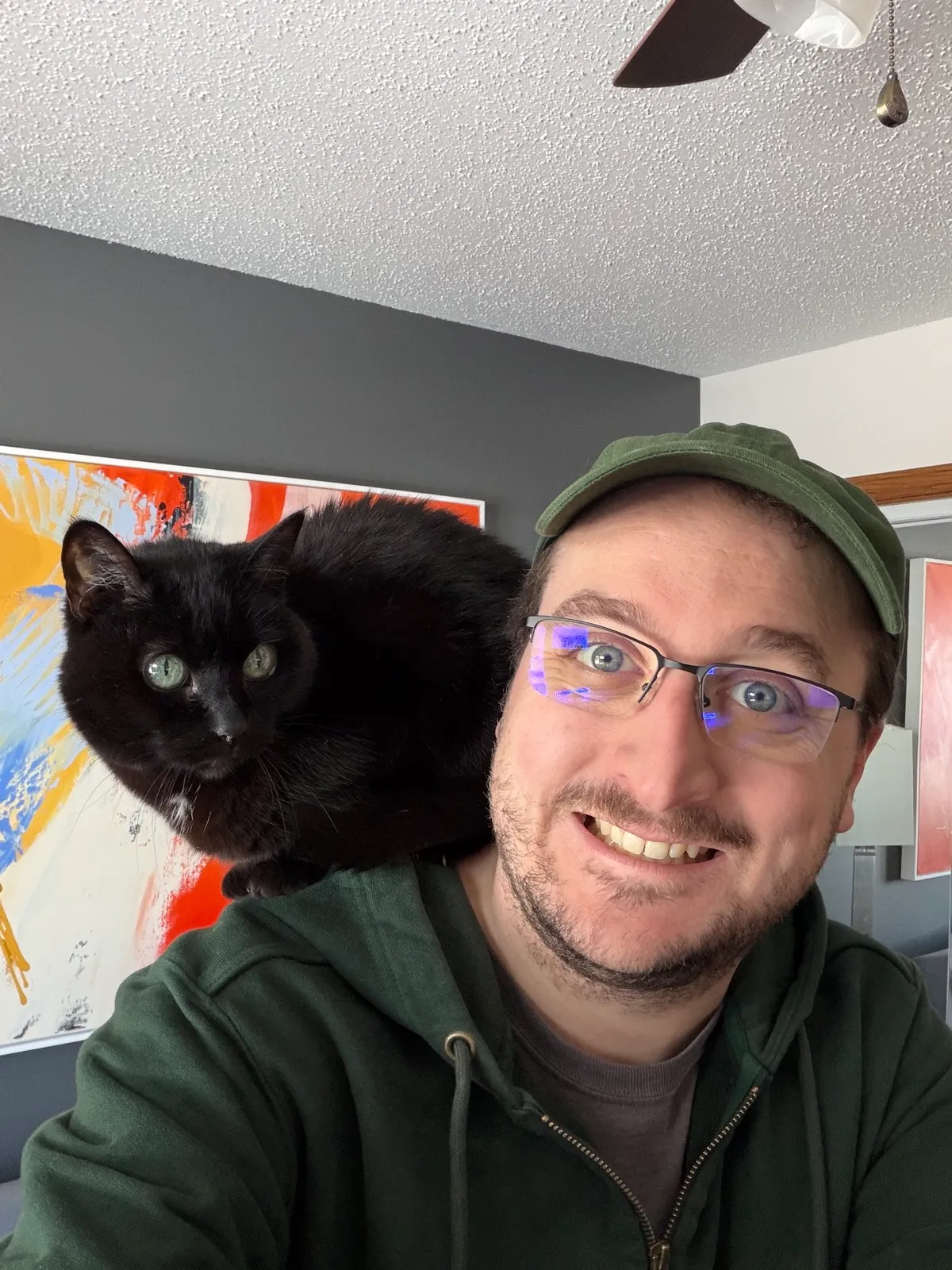 KOTEHOK perched on my shoulder while I take a selfie, her green eyes catching the light.