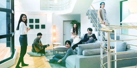 The Tokyo 2019-2020 cast in the modern house, gathered near the gold staircase.